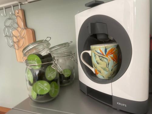 - une cafetière avec une tasse et des bocaux sur un comptoir dans l'établissement Le Tropical - Studio avec terrasse, à Angoulême