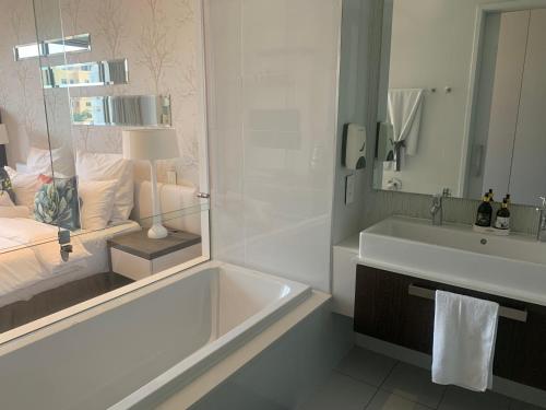 uma casa de banho com uma banheira, um lavatório e uma cama em Sandton Skye Stylish Apartment free WIFI & Gym em Joanesburgo