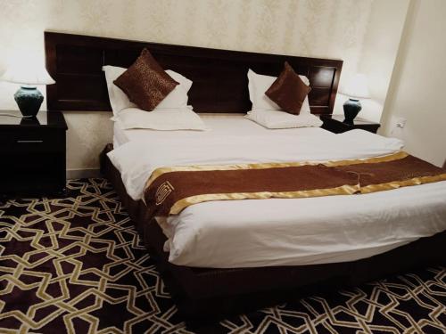 1 dormitorio con 1 cama grande con sábanas blancas y almohadas marrones en ركن الرمال en Sakaka