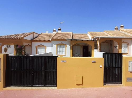 a yellow house with a black gate in front of it at Bungalow Flor de Lirio in Mazarrón
