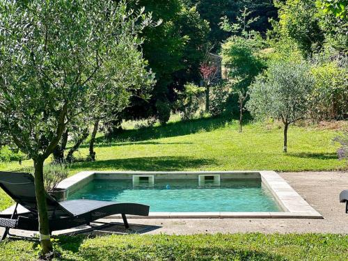 una piscina con un banco junto a un árbol en Charmant Logement avec piscine. en Valleraugue