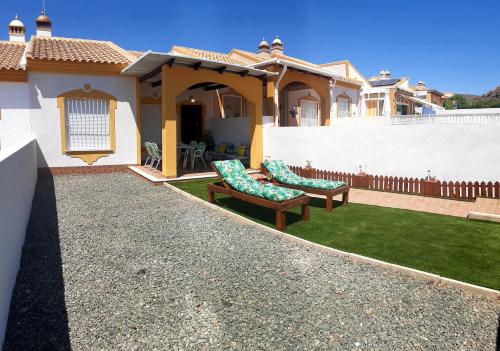 a house with two benches in the yard at Bungalow Flor de Lirio in Mazarrón