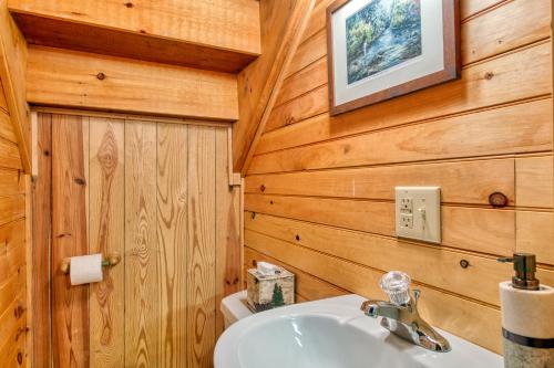 a bathroom with a white sink and wooden walls at Forest Hideaway in Maggie Valley