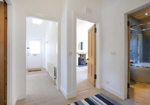 um corredor com paredes brancas e uma casa de banho com banheira em East Road Apartment em North Berwick