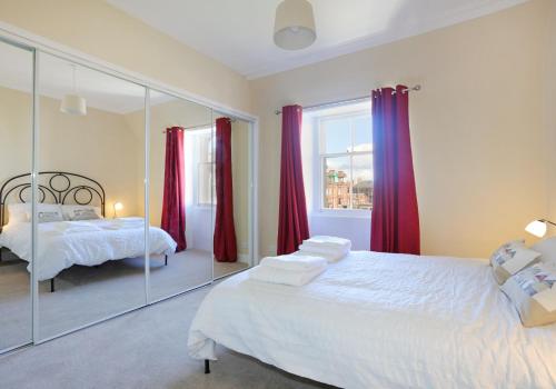 1 dormitorio con 2 camas y cortinas rojas en East Road Apartment en North Berwick