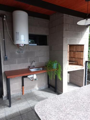 cocina al aire libre con fregadero y pared de ladrillo en casa de fin de semana en Termas de Río Hondo