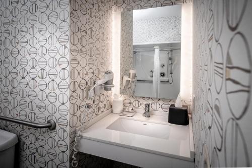 a white bathroom with a sink and a mirror at Holiday Inn Hotel & Suites Beckley by IHG in Beckley