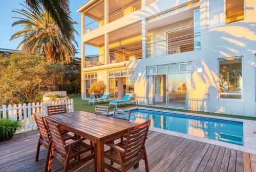 a house with a wooden table and chairs next to a swimming pool at Private Pool! Bantry Bay Large Flat with Solar in Cape Town