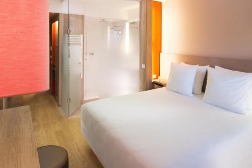 a bedroom with a large bed with white pillows at Oceania Paris Roissy CDG in Le Mesnil-Amelot