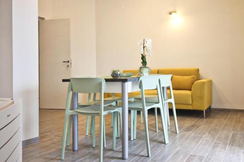 a dining room table and chairs with a yellow couch at Appartamenti Nicolò in Baunei