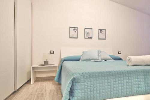 a white bedroom with a blue bed and a table at Appartamenti Nicolò in Baunei