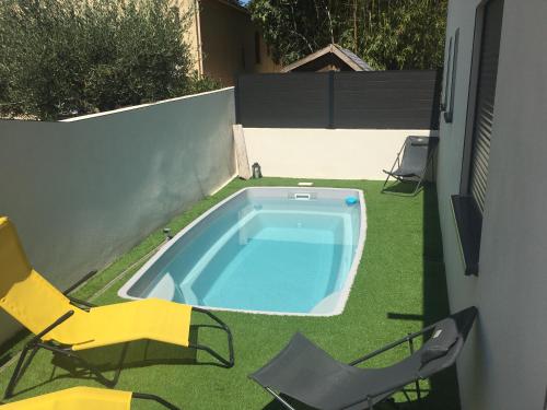 a backyard with a swimming pool and two chairs at Lou Mazet in Uchaud
