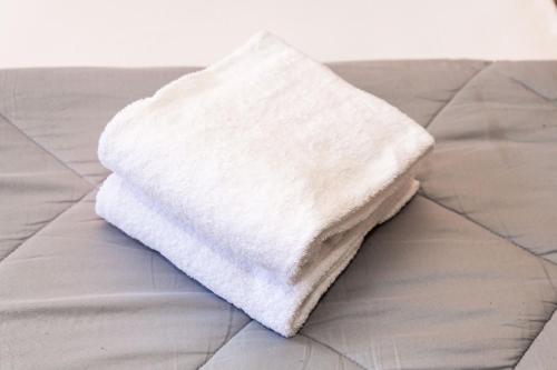 a stack of white towels sitting on a bed at Monti Guesthouse in Mestre