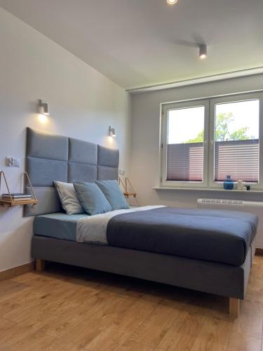 a bedroom with a blue bed with two windows at La Playa Apartments in Hel