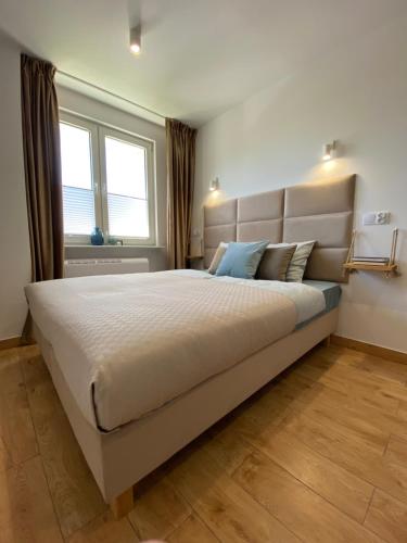 a large bed in a bedroom with a large window at La Playa Apartments in Hel