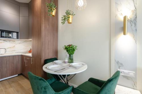 a dining room with a white table and green chairs at Modern new cozy apartment Kvartet Railway Station in Kyiv