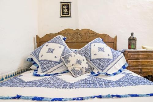 a bed with blue and white pillows on it at Dar Fatimazahra in Fès
