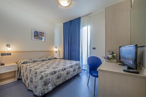 Habitación de hotel con cama y TV de pantalla plana. en Hotel Minerva en Lignano Sabbiadoro