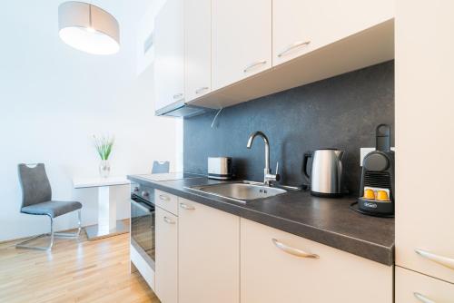 a kitchen with white cabinets and a sink at Vienna Residence, Marina Tower - Danube in Vienna