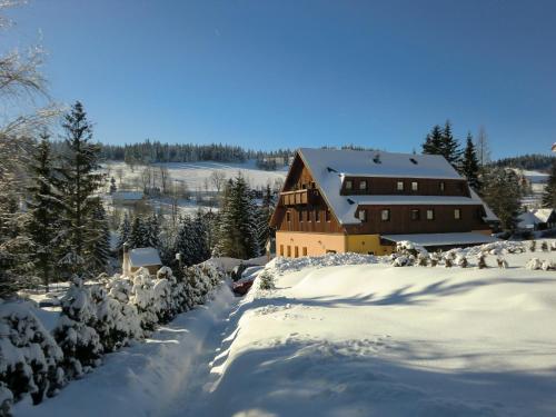 una casa está cubierta de nieve delante en Pension Hela, en Bedřichov