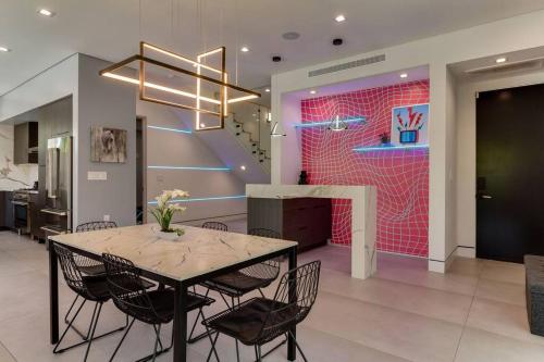 a dining room with a table and chairs and a pink wall at Posh Luxury Modern Home with Pool Spa and Rooftop Deck in Encino