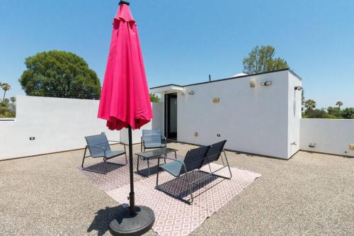 a pink umbrella and chairs on a patio at Posh Luxury Modern Home with Pool Spa and Rooftop Deck in Encino