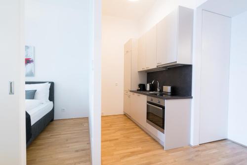 a kitchen with white cabinets and a bed in a room at Vienna Residence, Marina Tower - Danube in Vienna