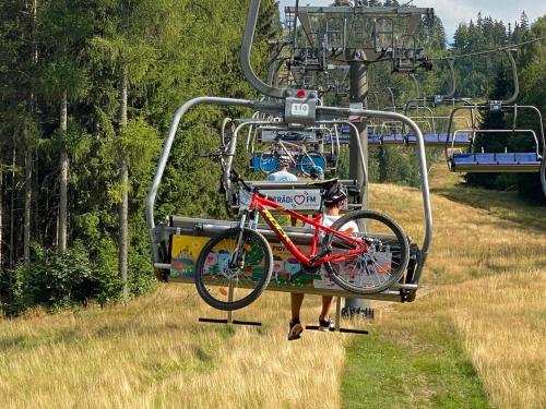 a person carrying a bike on a ski lift at Slunný byt v Jizerských horách 5 postelí in Tanvald