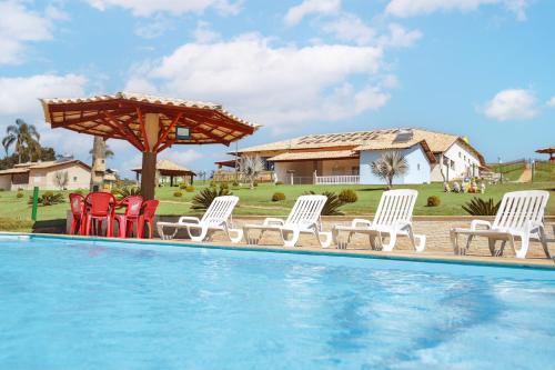 a group of chairs sitting next to a swimming pool at Complexo de Lazer Paraíso Rural in São Thomé das Letras