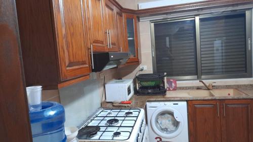 a kitchen with a stove and a washing machine at Cool Bayader apartment in Amman