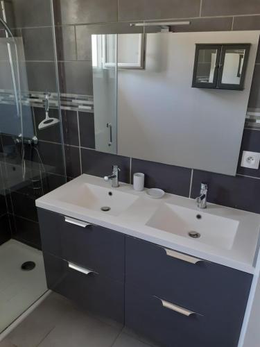 W łazience znajduje się biała umywalka i lustro. w obiekcie Maison familiale entre Dinard-St Malo-Dinan. w mieście Pleslin-Trigavou