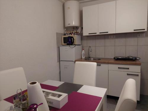 cocina con mesa, sillas y encimera en Apartman Amelaa, en Kulen Vakuf
