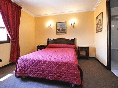 a bedroom with a large bed with a pink blanket at Les Geraniums in Le Barroux