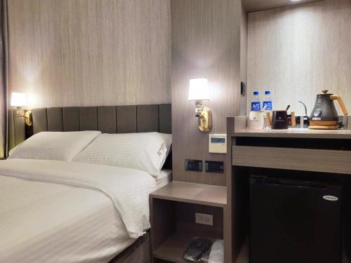 a bedroom with a bed and a desk with a computer at Hualien Pink Corner Hotel in Hualien City