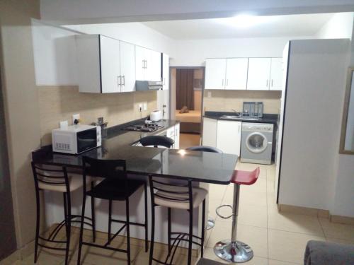a kitchen with a counter with stools and a microwave at Sandz accomodation at 108 in Durban