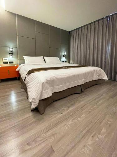 a bedroom with a large bed and a wooden floor at Hualien Pink Corner Hotel in Hualien City