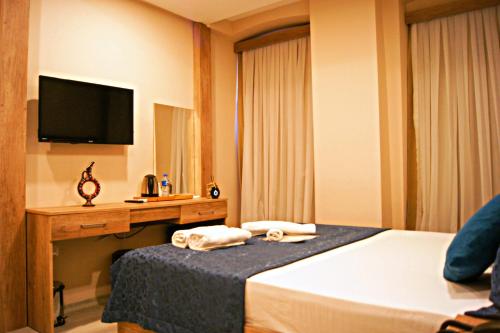 a hotel room with a bed and a desk with a television at Destinia Pera Suites in Istanbul
