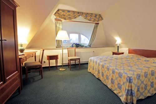a hotel room with a bed and a desk and a window at Parkhotel Oybin in Kurort Oybin