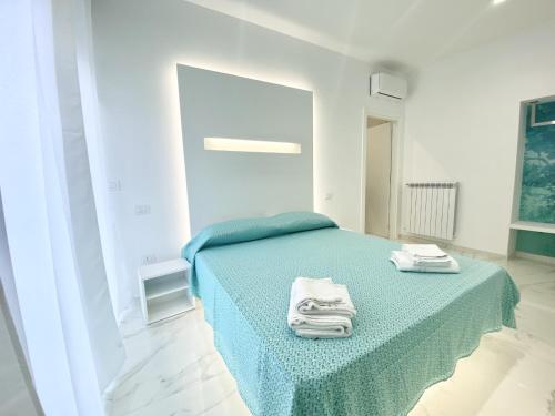 a bedroom with a green bed with towels on it at IL VIAGGIATORE RELAIS SUL MARE in Gaeta