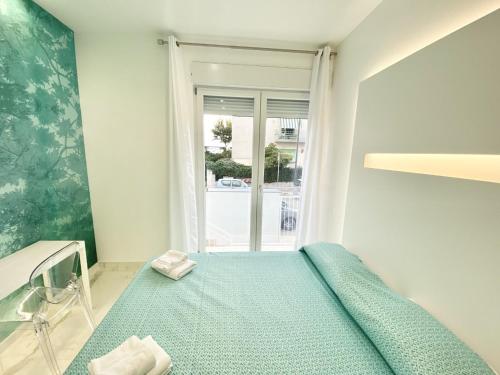 a small bedroom with a green bed with a window at IL VIAGGIATORE RELAIS SUL MARE in Gaeta