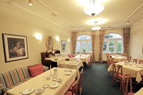 a dining room with tables and chairs with white tablecloths at Parkhotel Oybin in Kurort Oybin