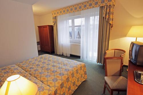 a hotel room with a bed and a window at Parkhotel Oybin in Kurort Oybin