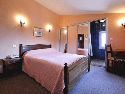 a bedroom with a large bed and a bathroom at Logis Hôtel Restaurant Les Géraniums in Le Barroux
