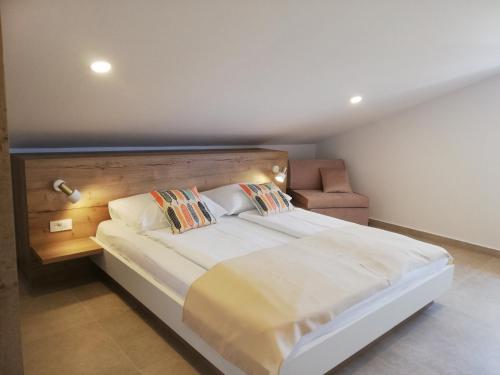 a bedroom with a large white bed and a chair at Haus Mit Meerblick in Lopar
