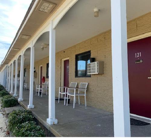 a porch with chairs and tables on a building at Outer Banks Motor Lodge in Kill Devil Hills