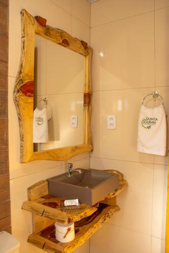 a bathroom with a sink and a mirror and towels at Quinta da Soliran Chalés Rural in Cambará