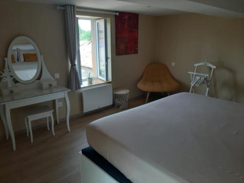 1 dormitorio con cama blanca y espejo en Logement Confortable dans résidence privée, en Amplepuis