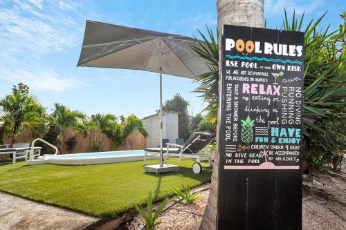 Kas di Bientu at Windsock Beach في كراليندايك: علامة مع مظلة بجوار حمام السباحة