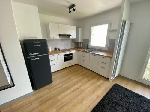 Il comprend une cuisine équipée d'un réfrigérateur noir et du parquet. dans l'établissement Le cœur de Rive gauche - Superbe T3 - parking - 082, à Rouen