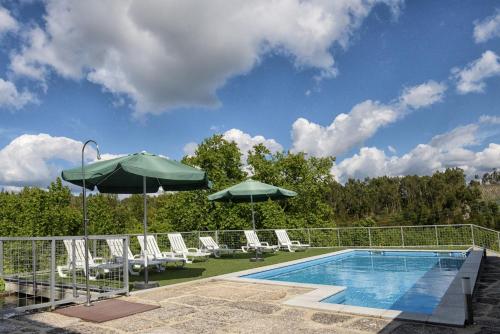 a swimming pool with lounge chairs and umbrellas next to a pool at Casa de Barreiros (Camélias de Basto) in Lamelas
